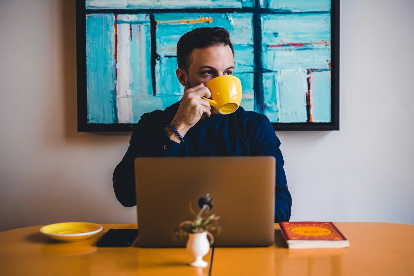 Una persona revisa cifras en su laptop con un café en la mano, de mañana, en silencio.